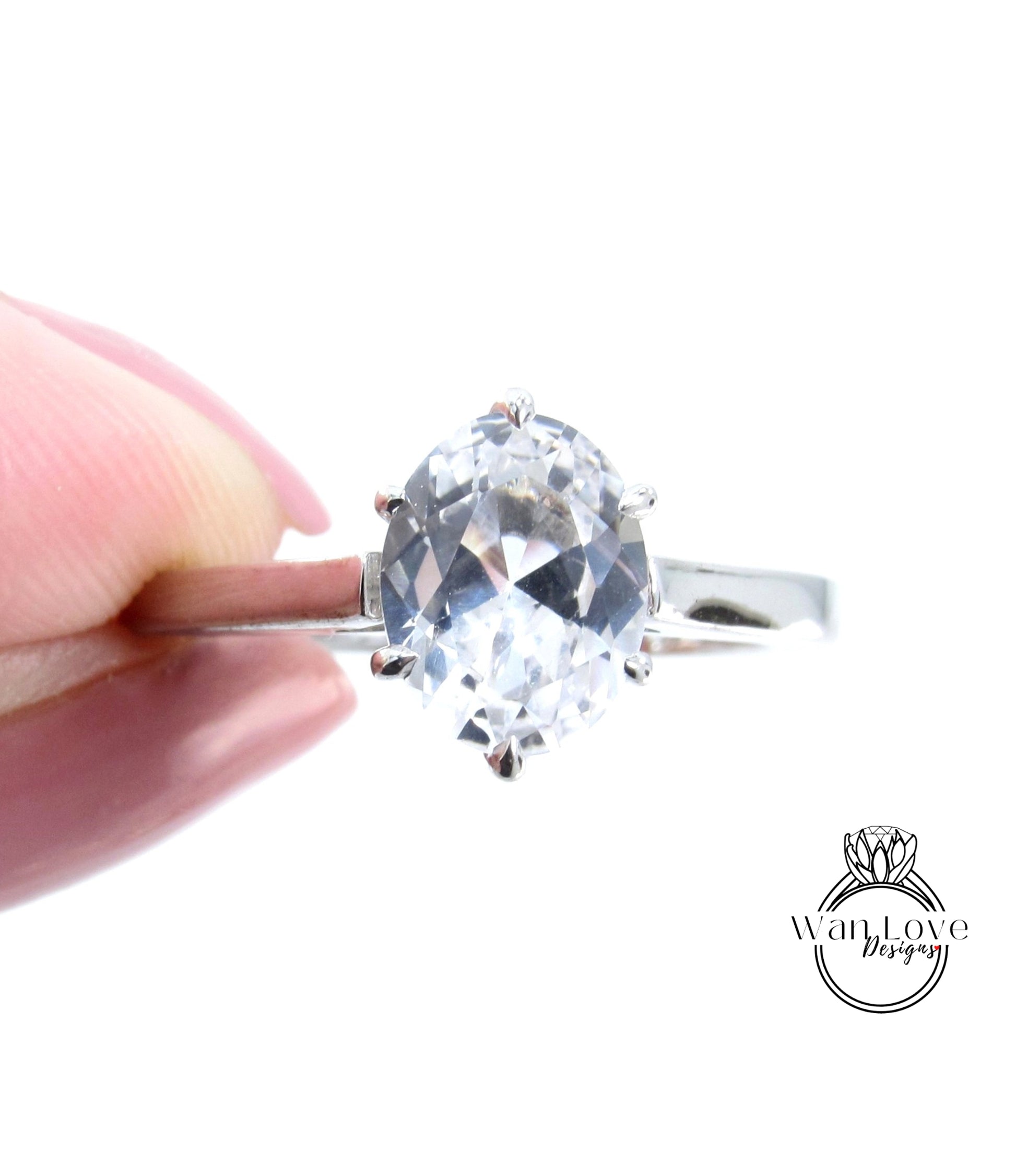 A close-up of a person's hand holding a diamond ring with a large, clear gemstone.