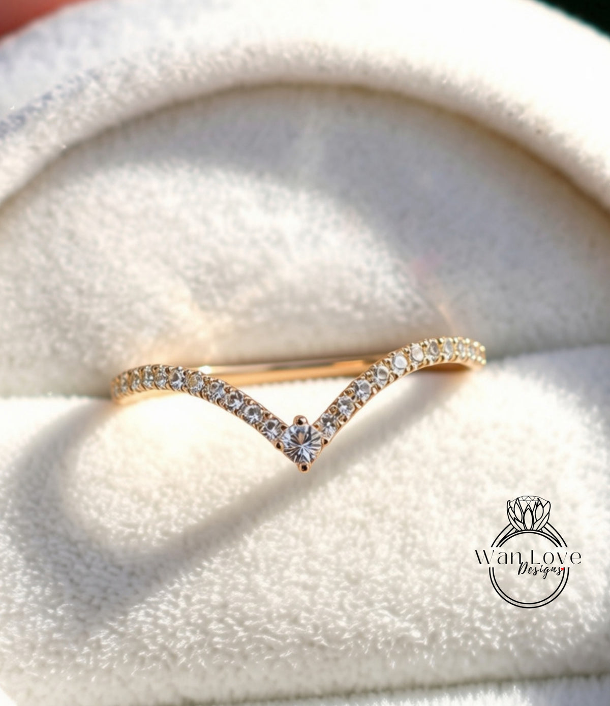 A gold ring with a diamond-encrusted band is displayed on a white fabric surface.