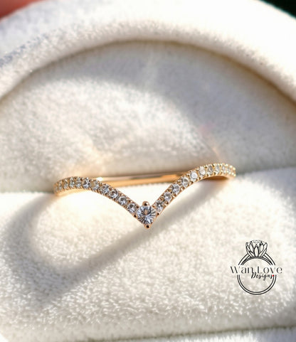 A gold ring with a diamond-encrusted band is displayed on a white fabric surface.