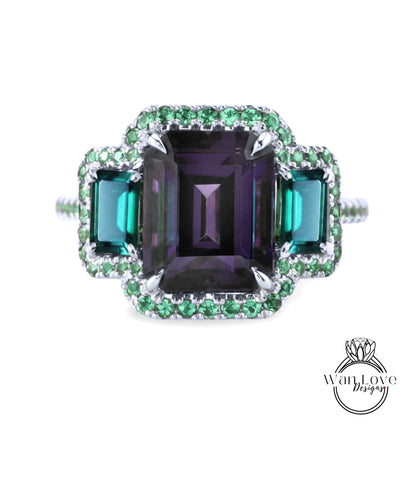 A ring with a large purple gemstone surrounded by smaller green gemstones, set in a silver band with a sparkling design.