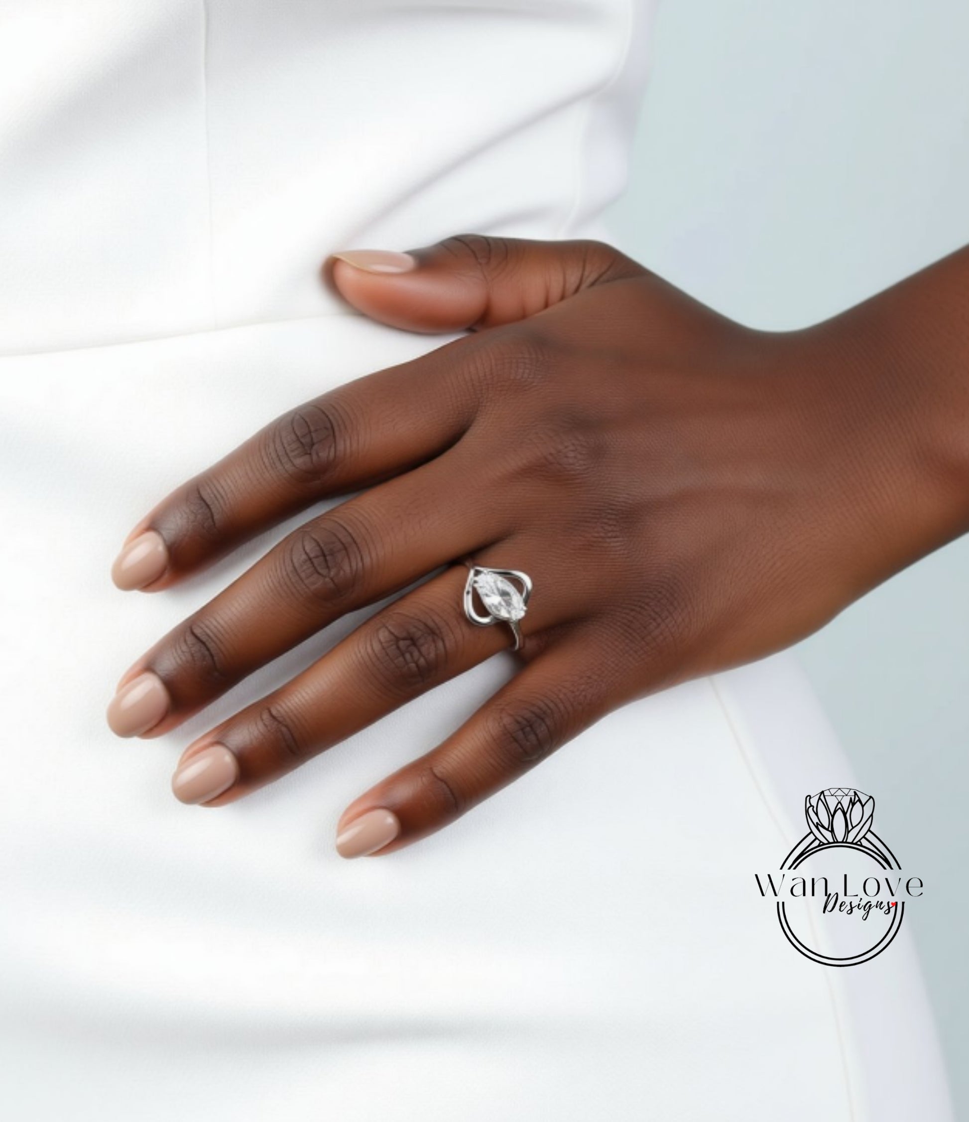 A close-up of a hand wearing a ring on the ring finger, with a white dress visible in the background.