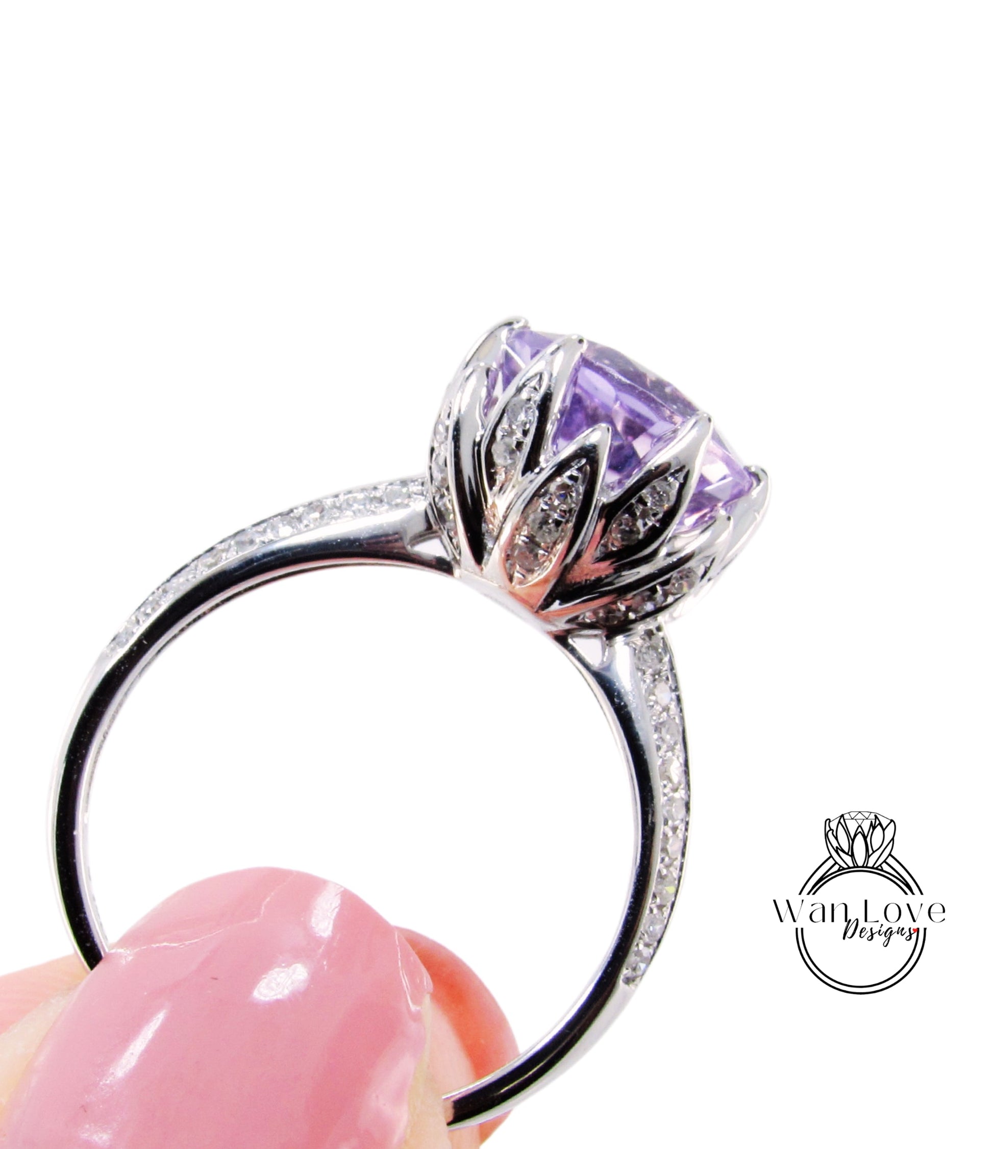 A close-up of a silver ring with a large purple gemstone, held in a person's hand against a white background.