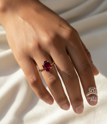 A close-up of a hand wearing a gold ring with a large, deep red gemstone.