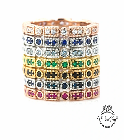 A stack of colorful rings with various gemstones, including diamonds and rubies, set in a gold-toned metal.