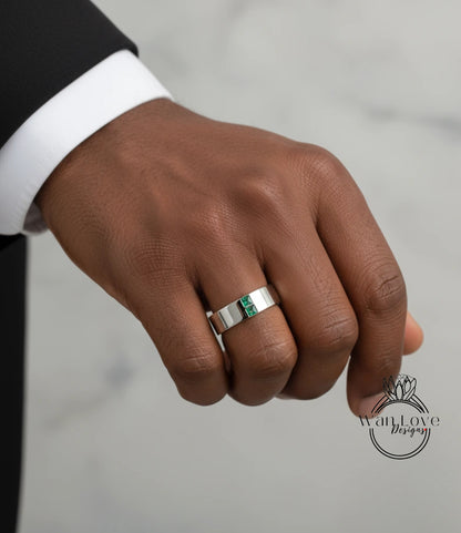 A close-up of a person's hand wearing a silver ring with a green gemstone.