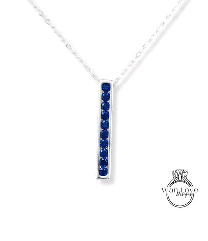 A silver necklace with a vertical row of blue gemstones, likely sapphires, set in a rectangular pendant.