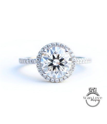 A close-up view of a diamond engagement ring with a large, round brilliant-cut diamond set in a halo of smaller diamonds, surrounded by a band of smaller diamonds.