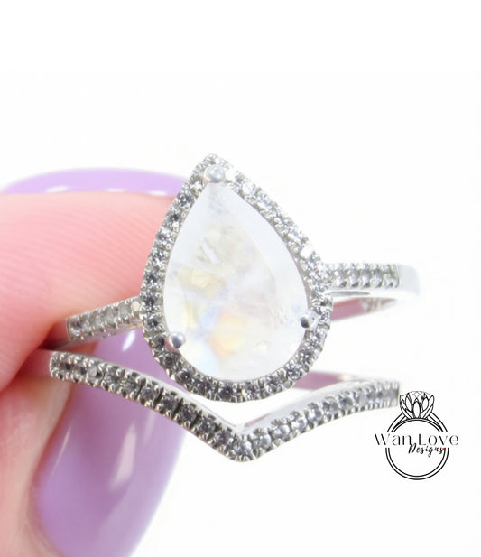 A close-up image of a silver ring with a large, clear gemstone, possibly a moonstone, set in a halo of smaller stones.