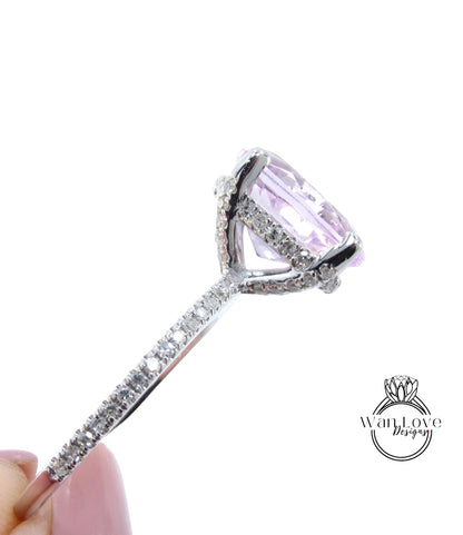 A close-up view of a large, pink gemstone set in a silver ring with a diamond-encrusted band.