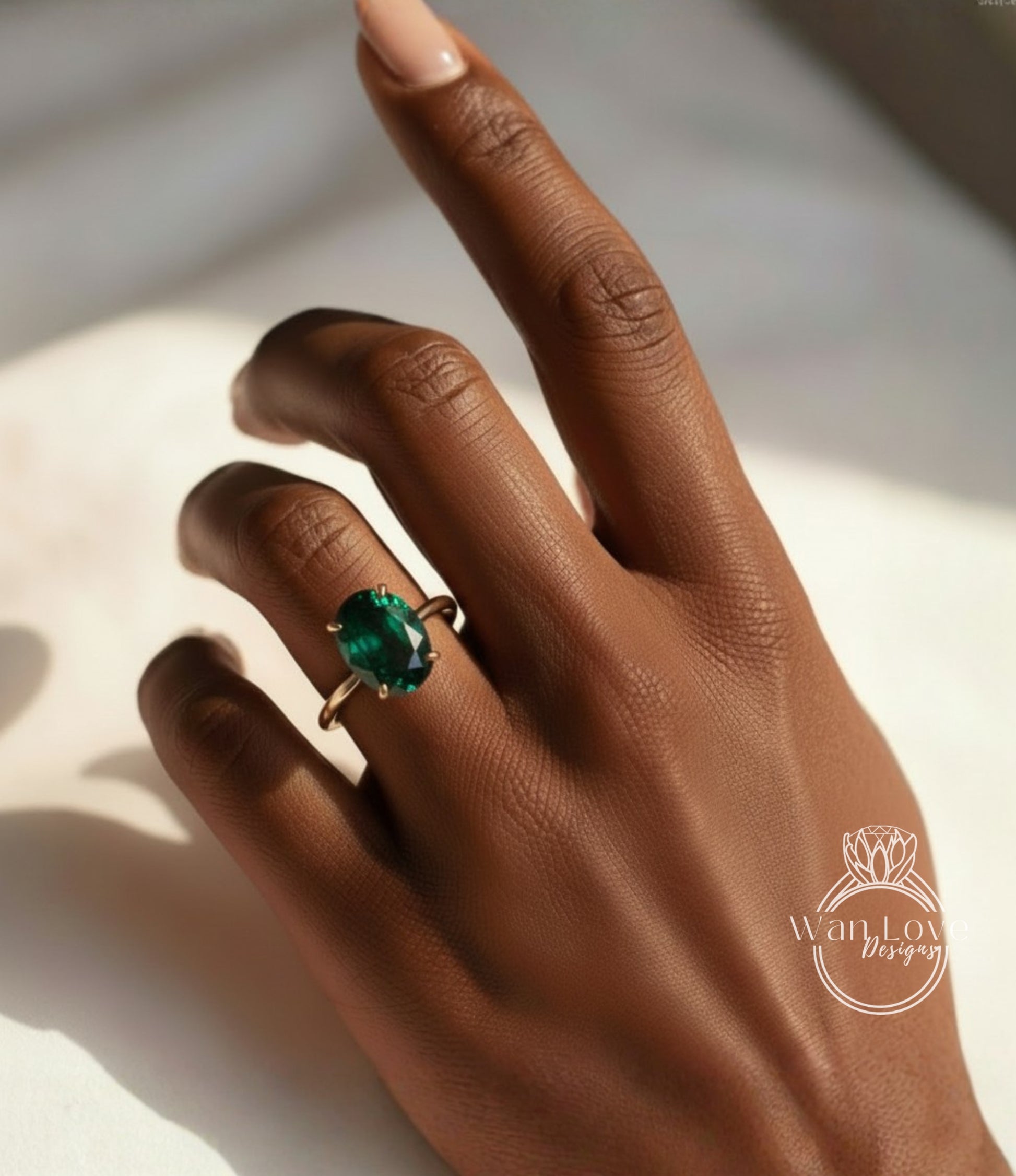 A close-up of a hand wearing a ring with a large green gemstone.