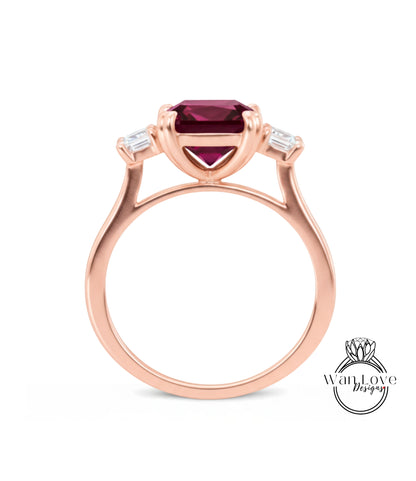 A rose gold ring with a large, deep red gemstone set in the center, surrounded by smaller diamonds.
