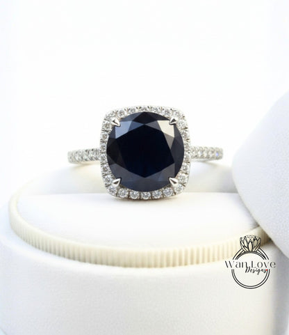 A close-up image of a diamond engagement ring with a large blue gemstone set in a halo of smaller diamonds.