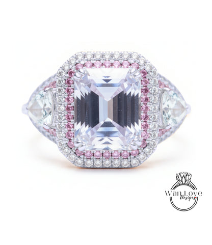 A large, clear gemstone ring with a halo of smaller diamonds around it, set in a silver and pink metal band.