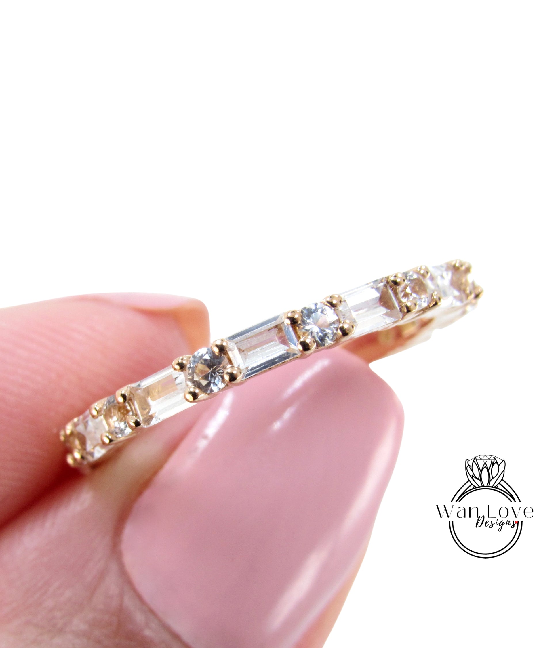 A close-up image of a person's hand holding a gold ring with clear gemstones.