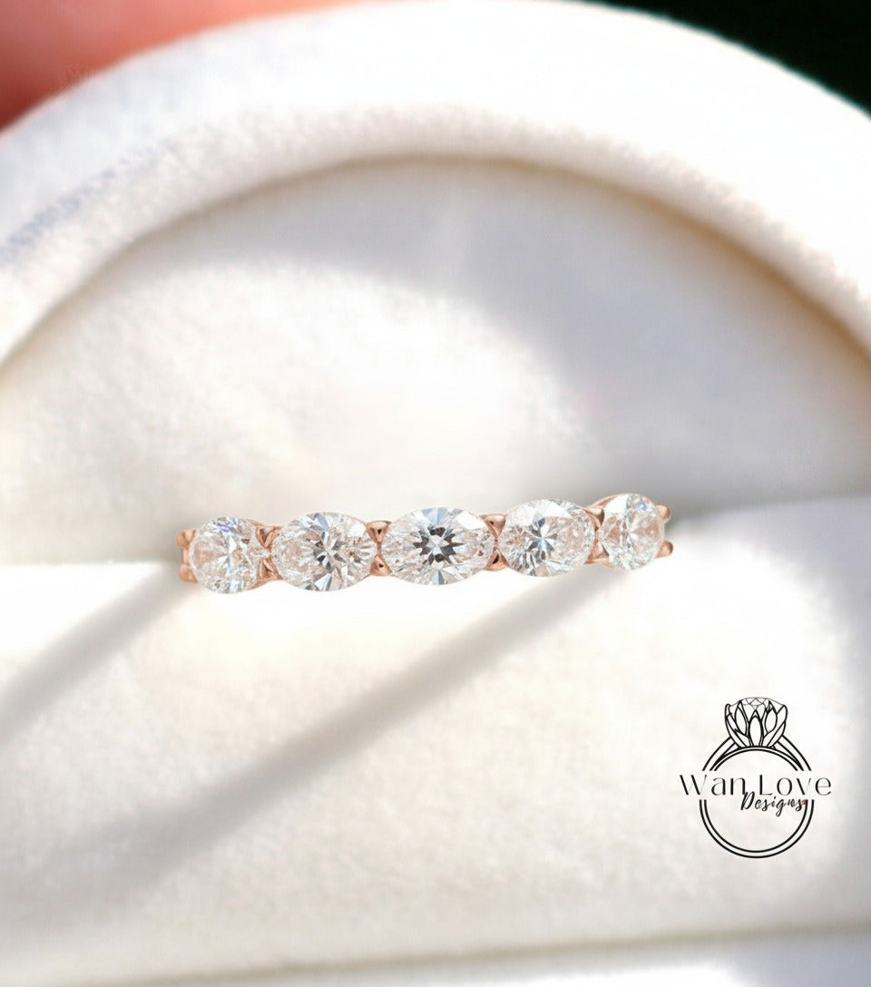 A close-up image of a gold ring with a row of five round diamonds set in the band.