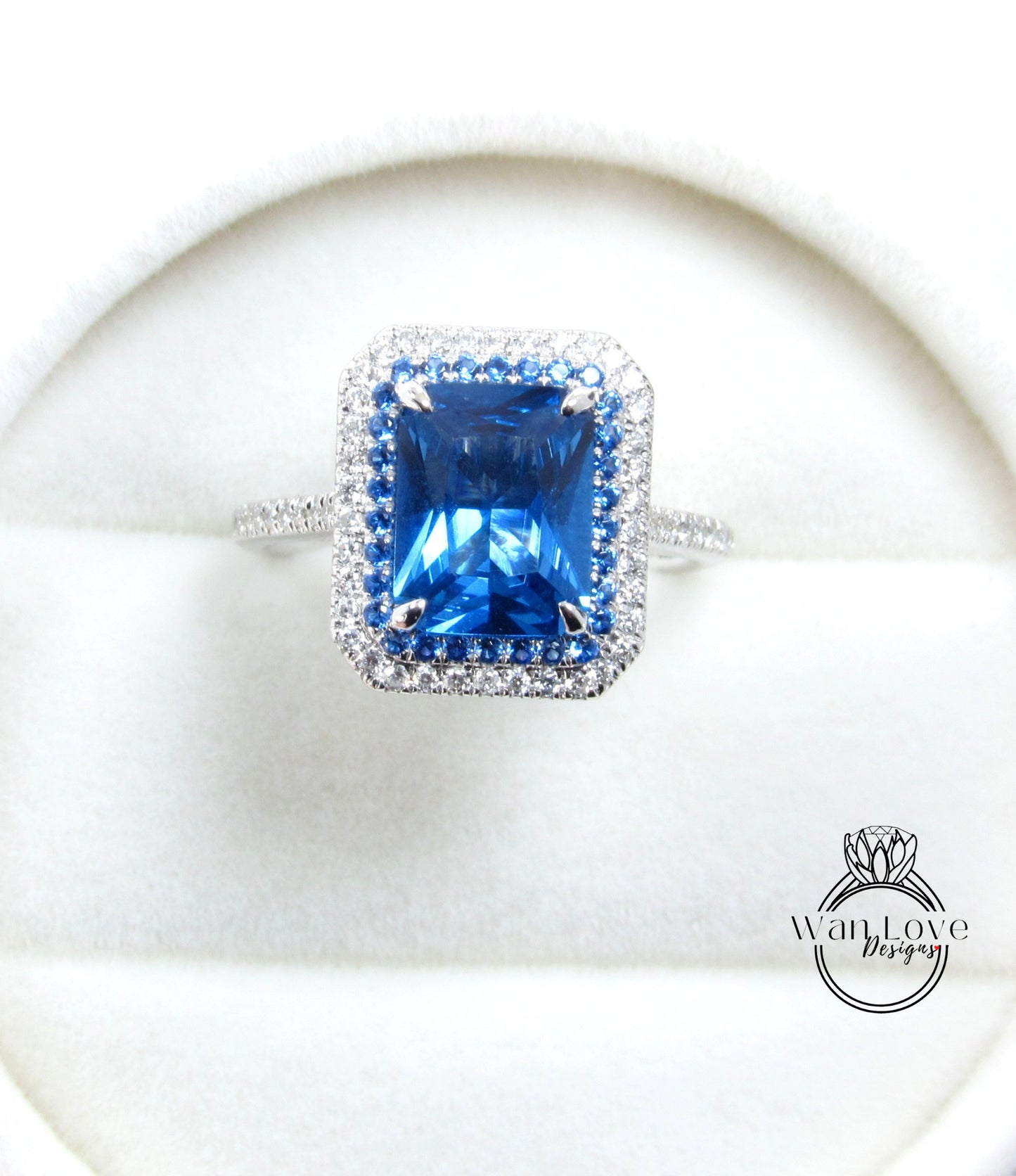 A large, blue gemstone ring with a halo of smaller diamonds around it, displayed on a white background.
