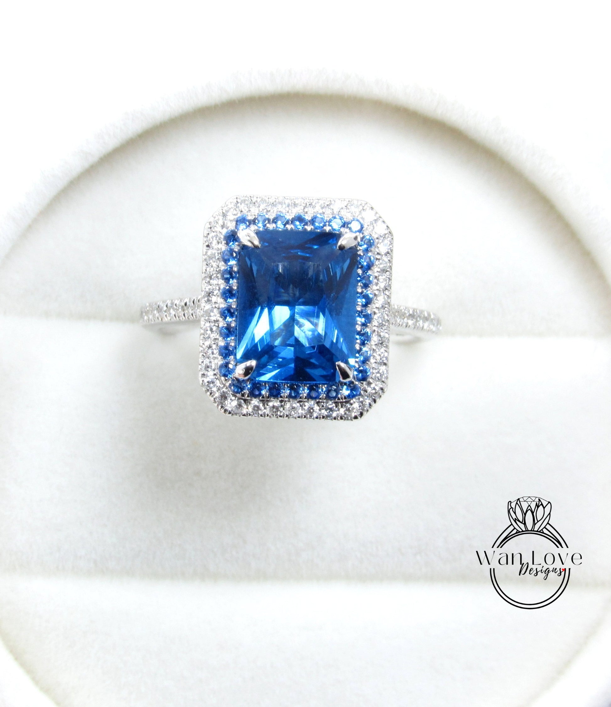 A large, blue gemstone ring with a halo of smaller diamonds around it, displayed on a white background.