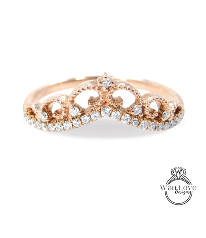 A gold-colored ring with a decorative crown-like design and small diamonds set in the center.