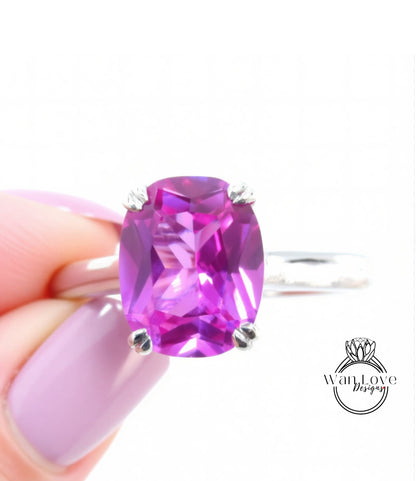 A hand holding a ring with a large, vibrant purple gemstone.