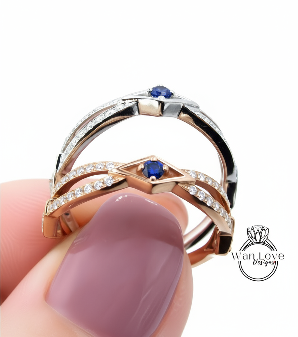A close-up of a person's hand holding a ring with a pinkish-pink gemstone and a blue gemstone.