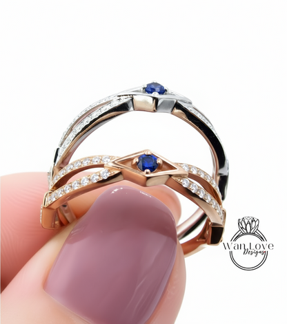 A close-up of a person's hand holding a ring with a pinkish-pink gemstone and a blue gemstone.