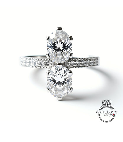 A close-up of a diamond engagement ring with two large, round diamonds set in a silver band.