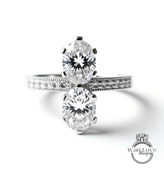 A close-up of a diamond engagement ring with two large, round diamonds set in a silver band.