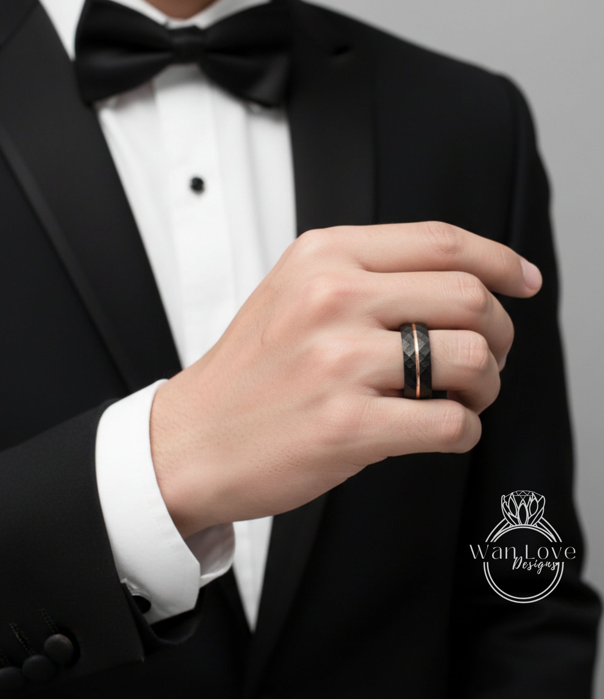 A close-up of a person's hand wearing a black tuxedo and a ring on the finger.