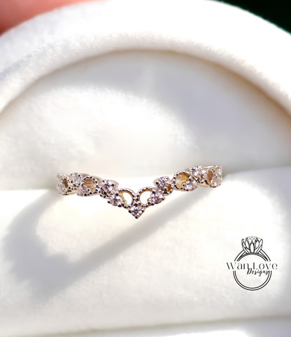 A close-up view of a gold ring with a heart-shaped design, placed on a white surface.