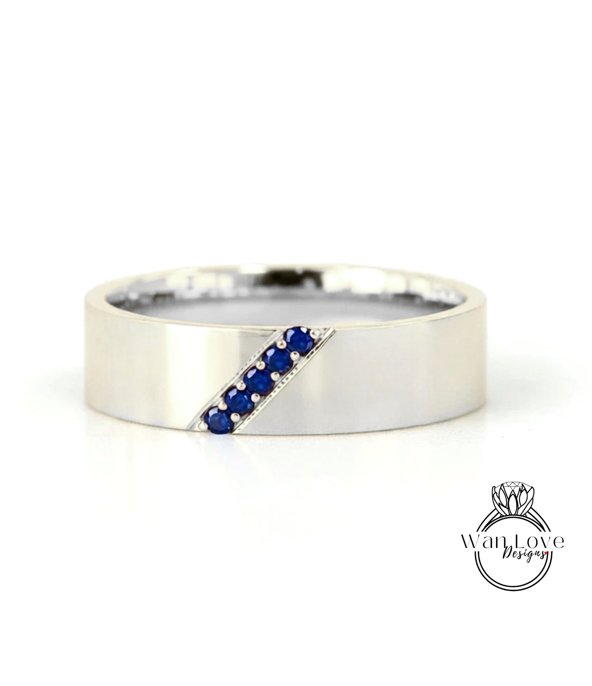 A silver band ring with a diagonal line of blue gemstones.