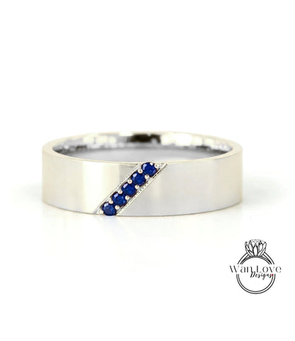 A silver band ring with a diagonal line of blue gemstones.