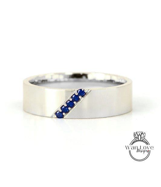 A silver band ring with a diagonal line of blue gemstones.