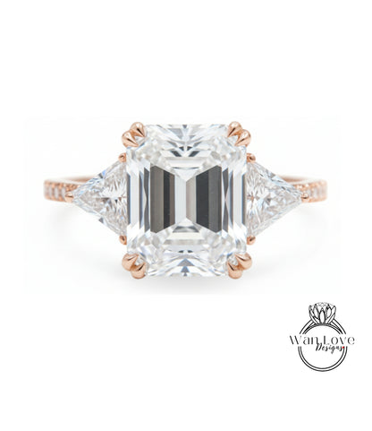 A large, clear diamond engagement ring with a prominent central diamond surrounded by smaller diamonds on either side.