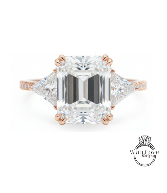 A large, clear diamond engagement ring with a prominent central diamond surrounded by smaller diamonds on either side.