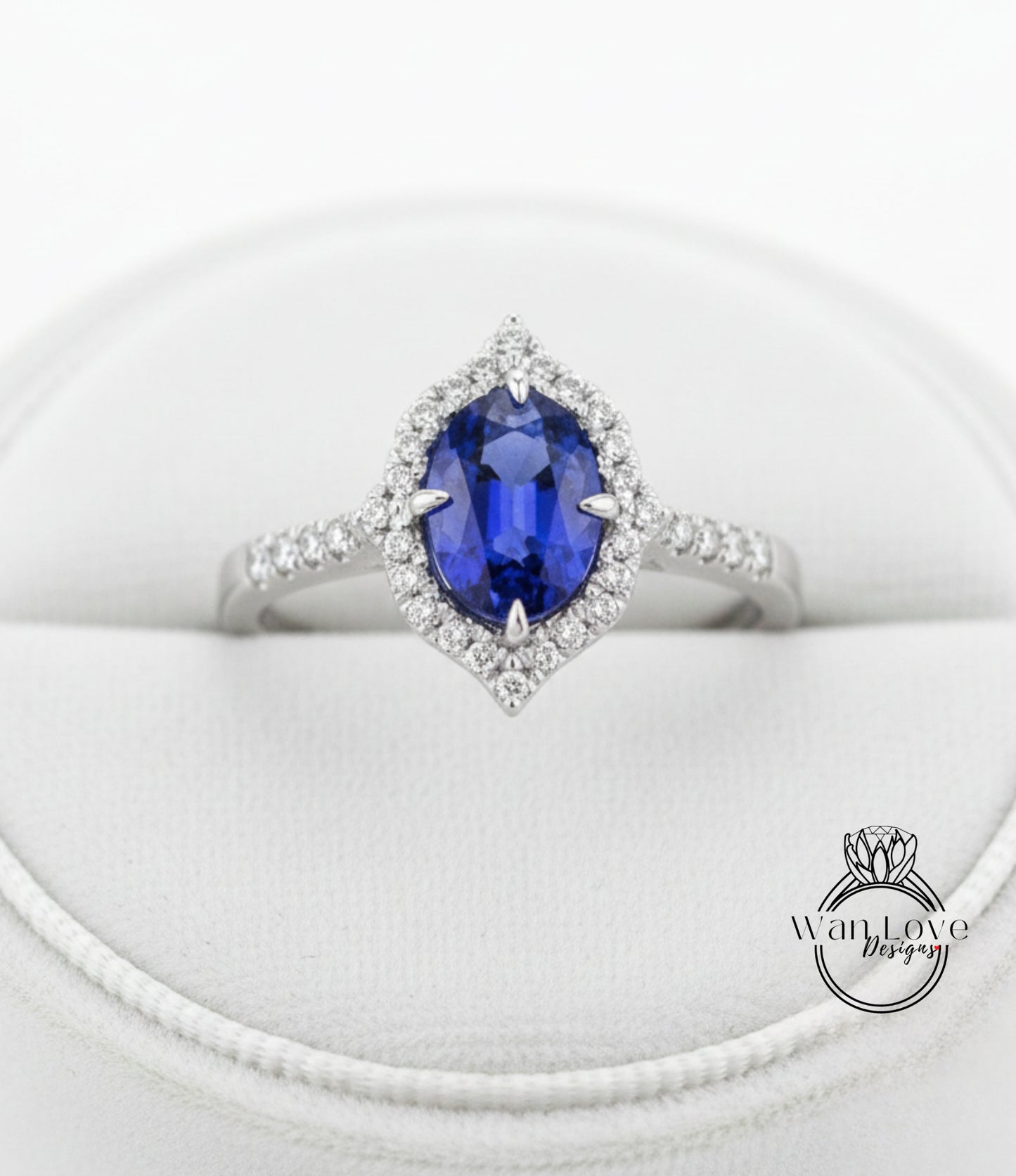 A close-up view of a diamond engagement ring with a large oval-shaped blue gemstone surrounded by a halo of smaller diamonds.