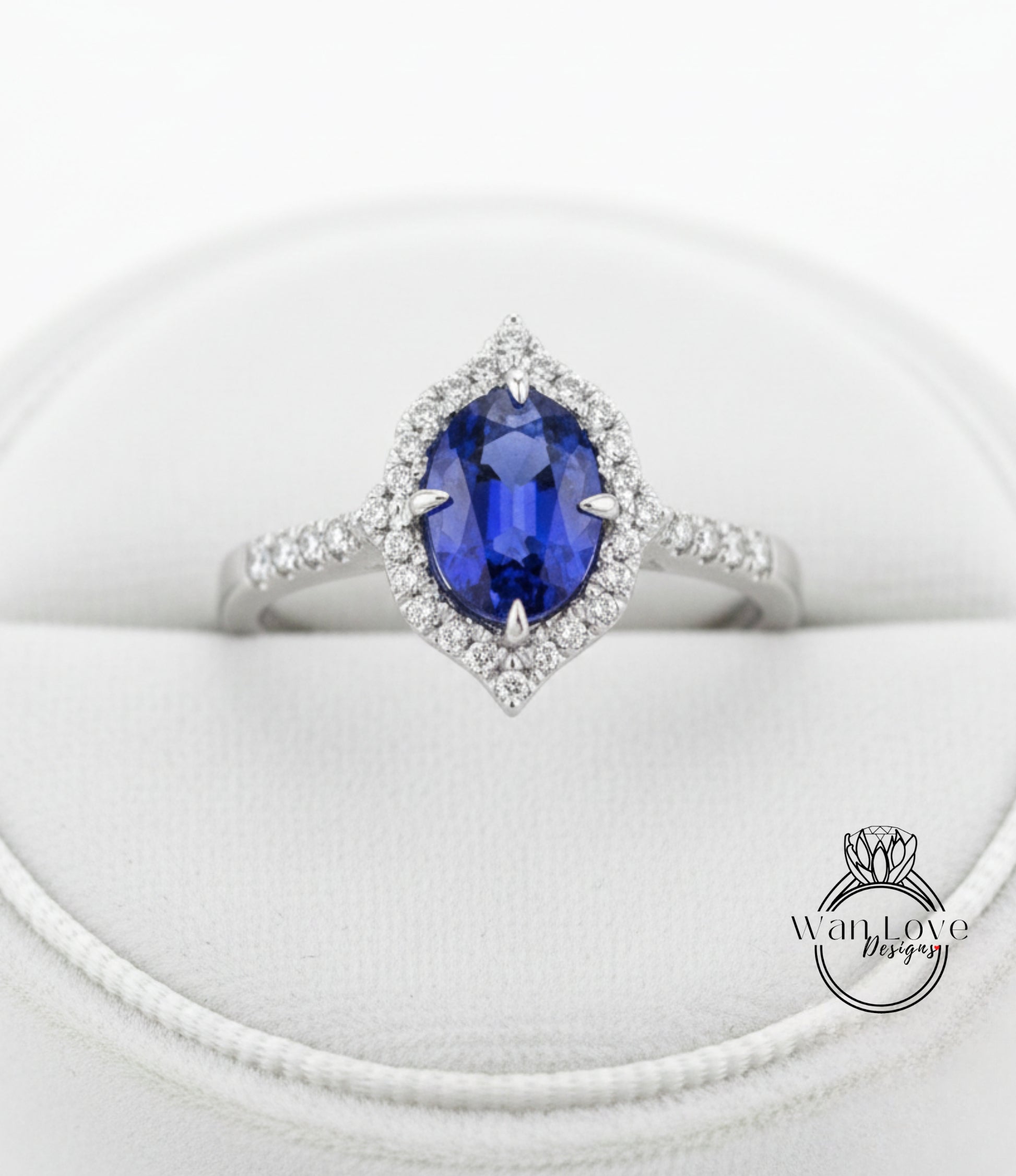 A close-up view of a diamond engagement ring with a large oval-shaped blue gemstone surrounded by a halo of smaller diamonds.