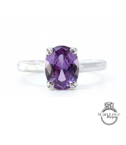A silver ring with a large oval-shaped purple gemstone, which appears to be a sapphire.