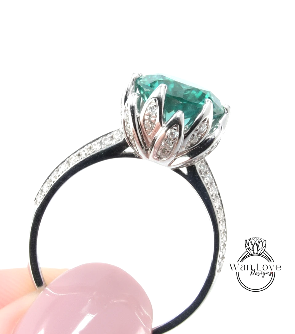 A close-up of a silver ring with a large, green gemstone set in a decorative flower-like design.