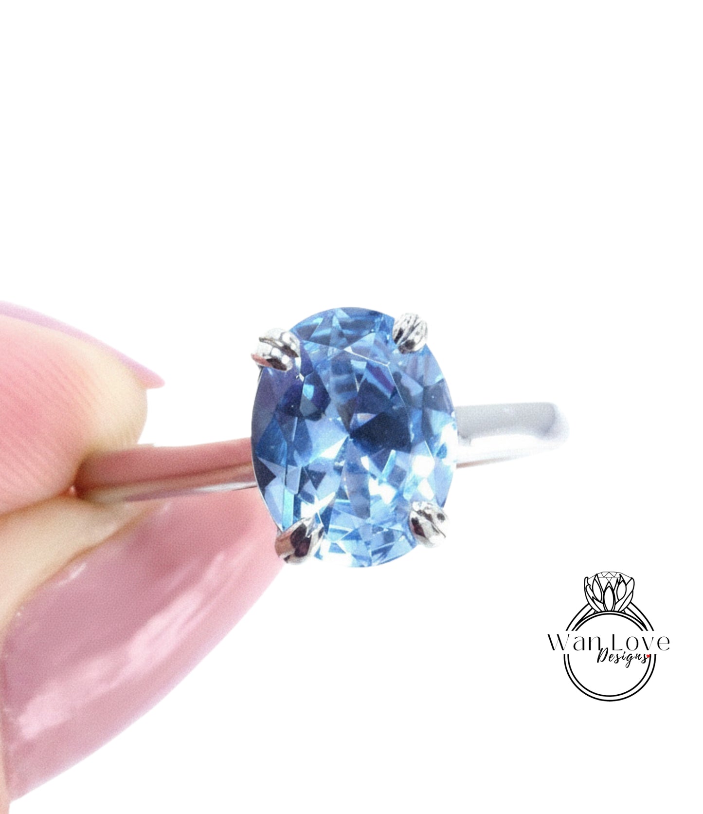 A close-up image of a person's hand holding a ring with a blue gemstone, likely a sapphire or blue topaz.
