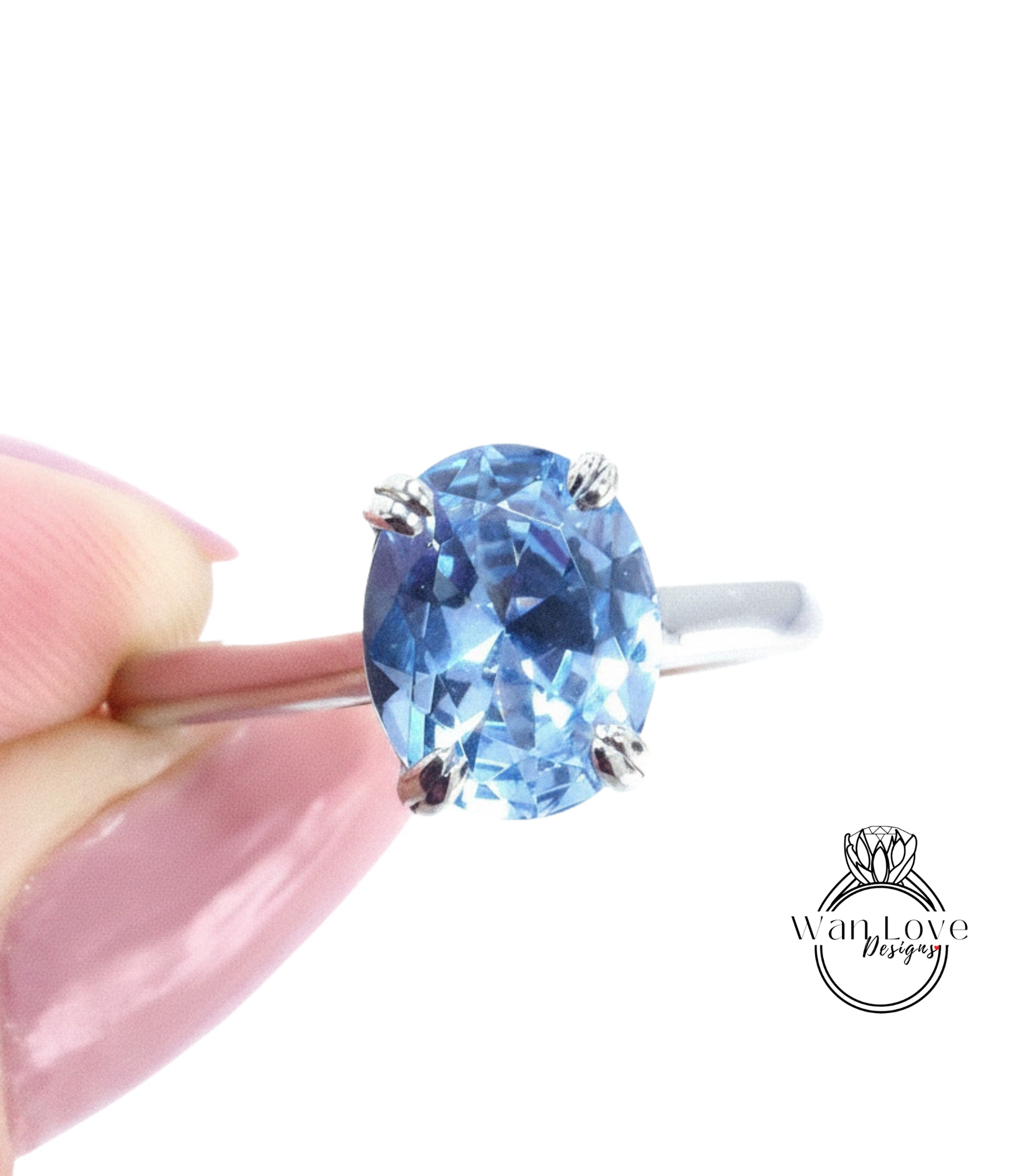 A close-up image of a person's hand holding a ring with a blue gemstone, likely a sapphire or blue topaz.