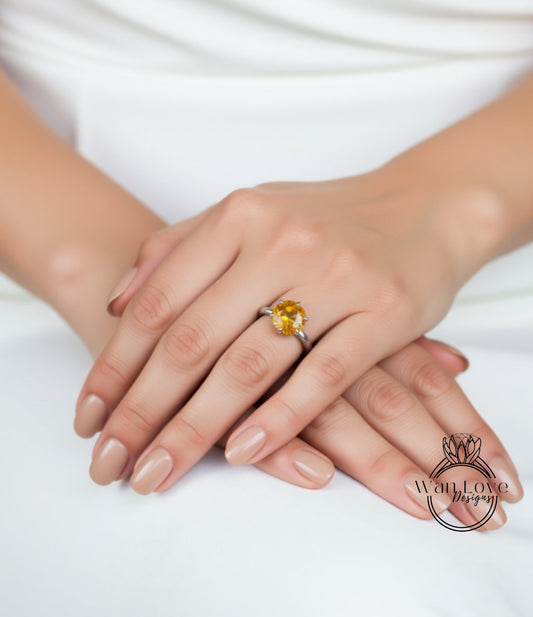 A close-up image of a person's hands wearing a ring with a large yellow gemstone.
