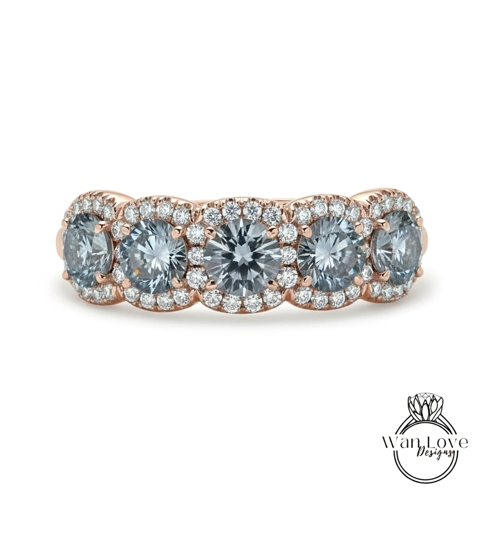 A ring with a row of blue diamonds set in a halo of smaller diamonds, all set in a rose gold band.