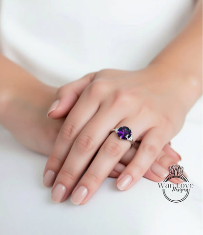 A close-up of a person's hand wearing a ring with a large purple gemstone.