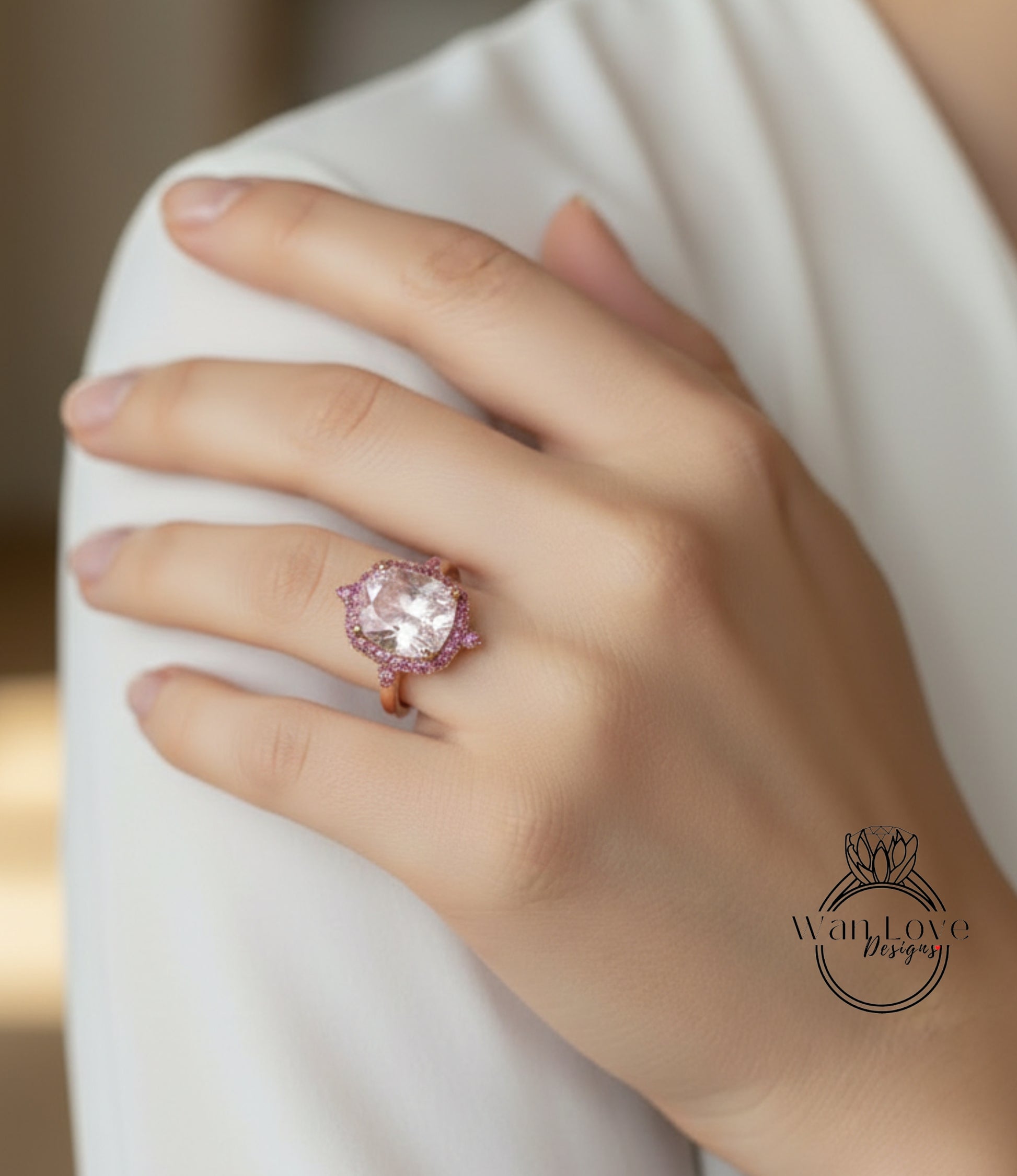 A close-up of a person's hand wearing a large, ornate ring with a pink gemstone.