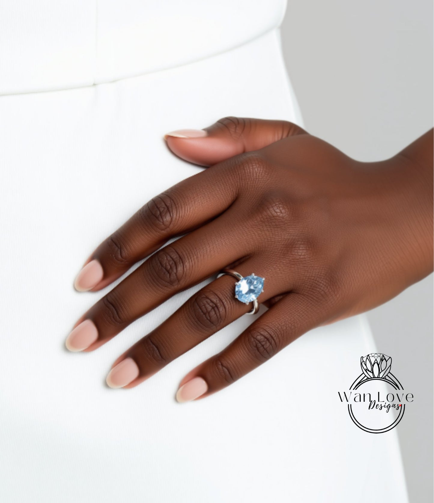 A close-up of a hand wearing a ring with a blue gemstone.