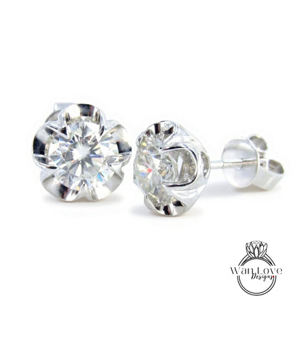 A pair of elegant diamond stud earrings with a large, brilliant-cut diamond set in a silver metal frame.