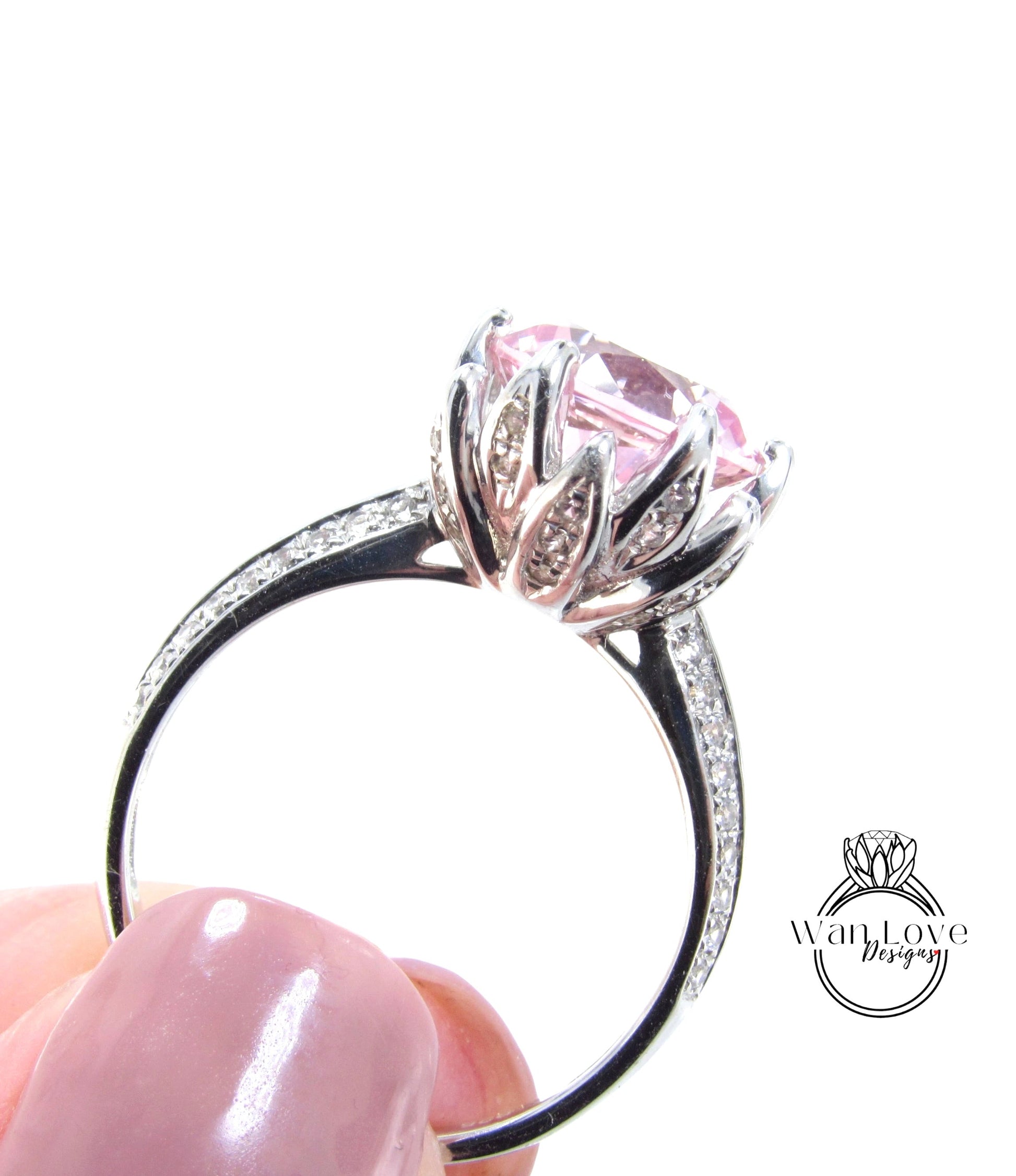 A close-up of a silver ring with a large pink gemstone, held in a person's hand.