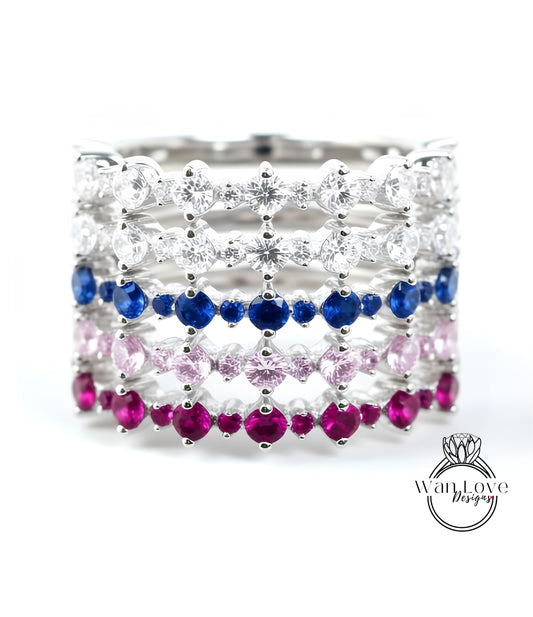 A silver ring with a row of colorful gemstones, including diamonds and rubies, arranged in a decorative pattern.