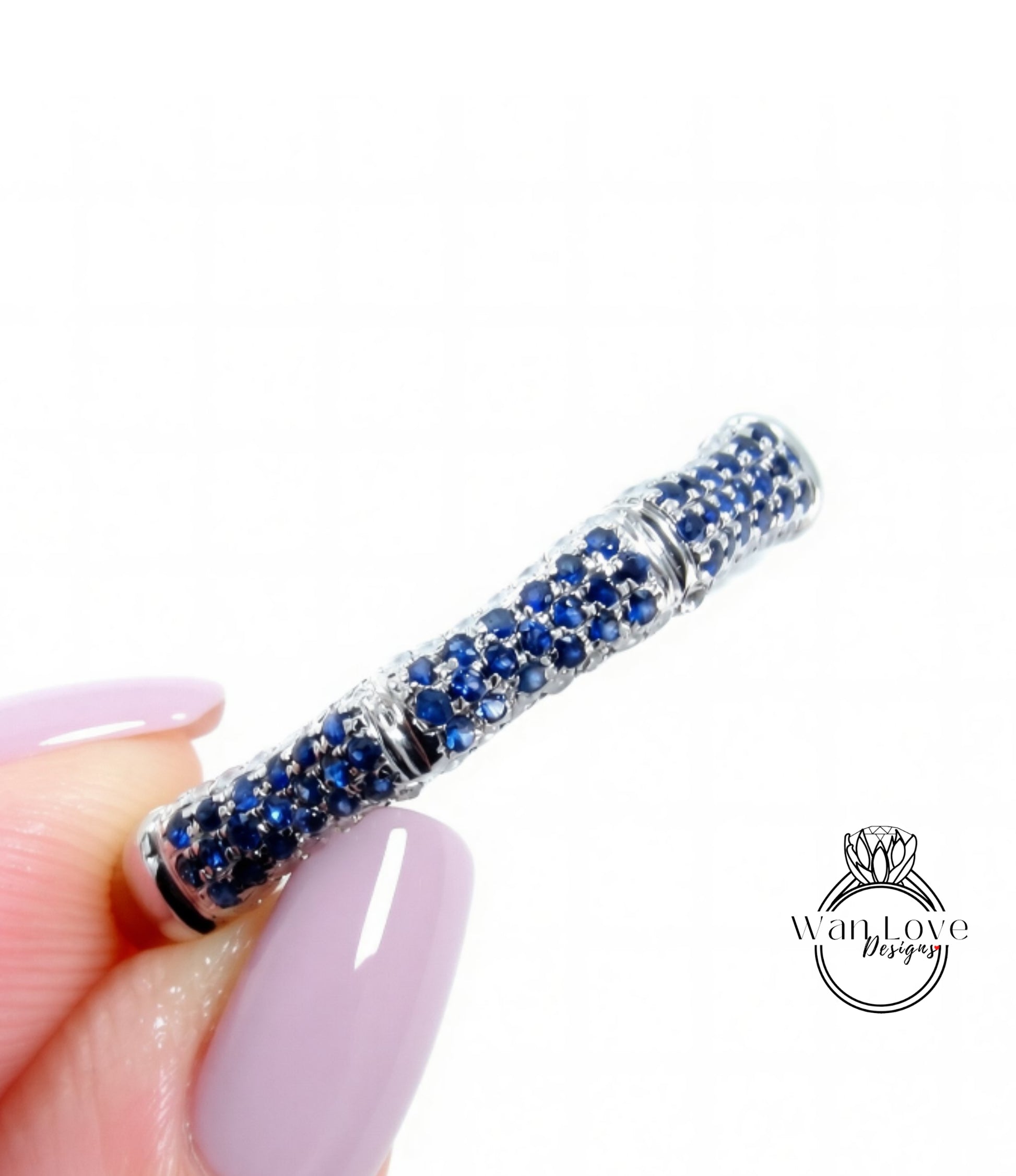 A close-up image of a person's hand holding a ring with a blue gemstone design.
