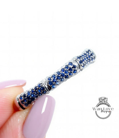A close-up image of a person's hand holding a ring with a blue gemstone design.